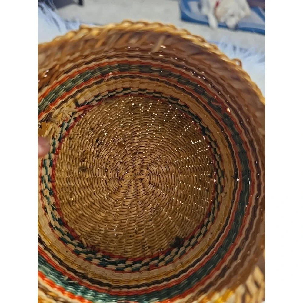 The image displays a‎ small, round, hand-woven basket with a lid, typically made